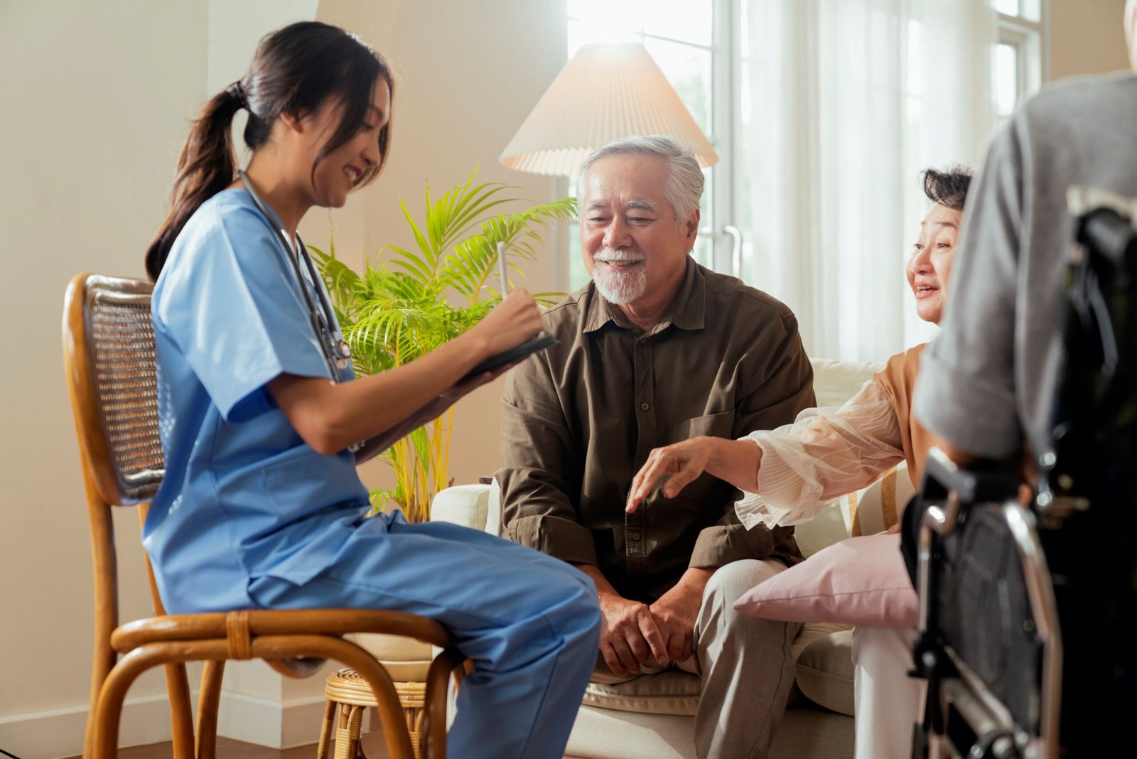 happiness cheerful elderly woman men talking with female caregiver nurse doctor having health checking consult living areacaretakers with senior couple sitting living room nursing home